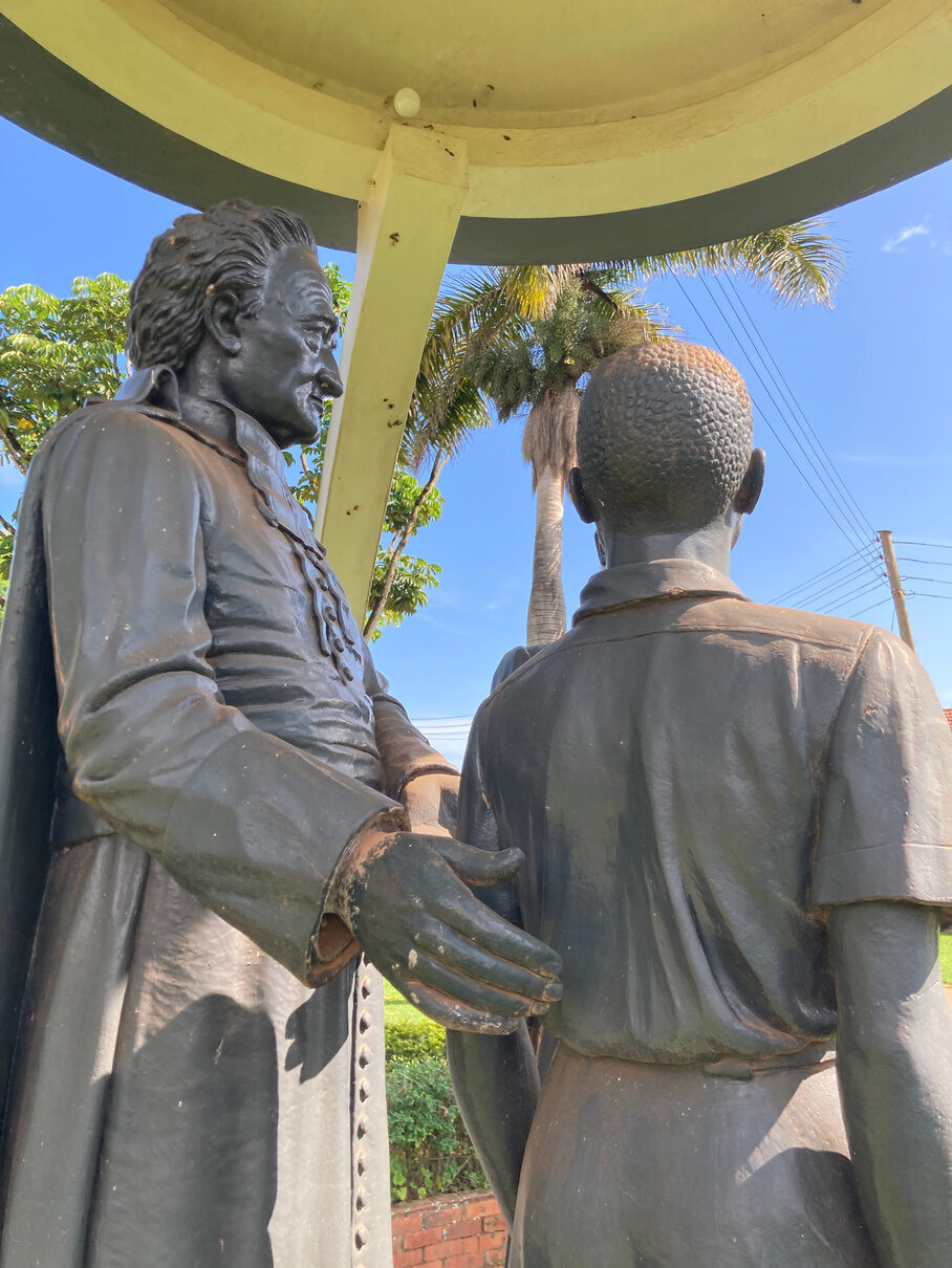 The priest's hand resting on the boy's shoulder, seen from behind.