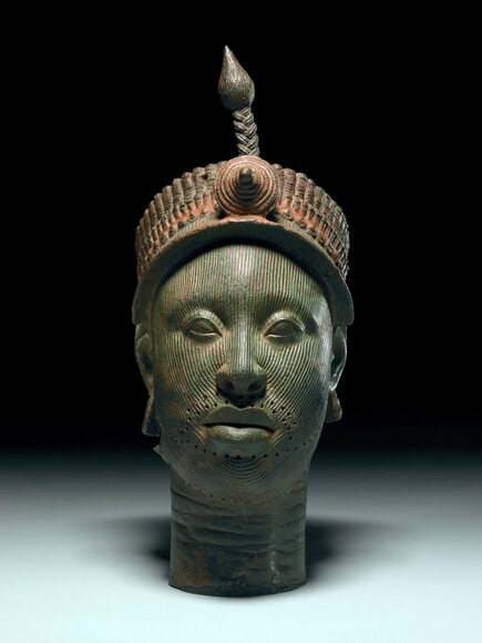A crowned Ife head lit against a black background.